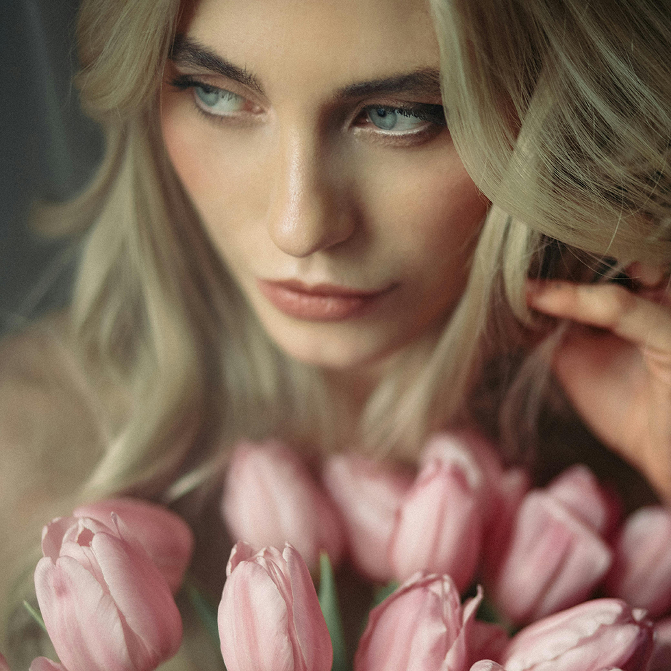 Schönes Gesicht einer Frau mit rosa Tulpen