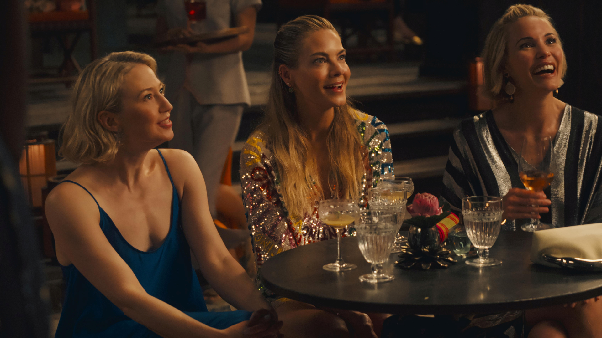 White Lotus zeigt toxische Freundschaft: 3 blonde Frauen sitzen nebeneinander in einem Restaurant in Thailand