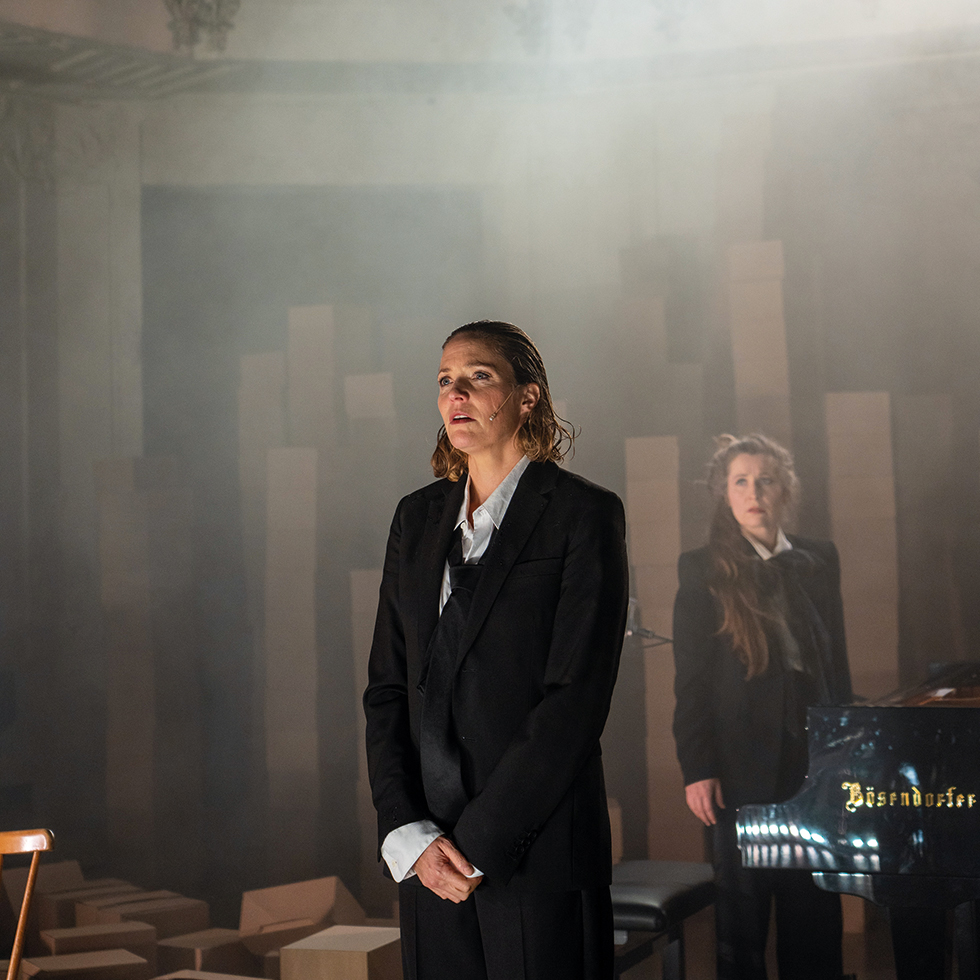 2 Frauen in schwarzen Anzügen auf einer Theaterbühne