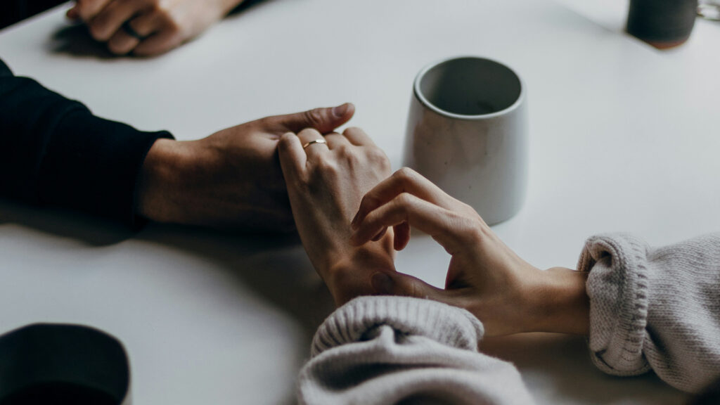 Tisch mit Kaffeetasse – Mann und Frau Händchenhaltend