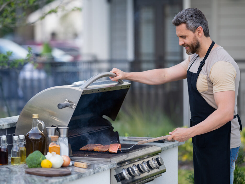 Barbecue concept. Middle aged hispanic man in apron for barbecue. Roasting and grilling food. Roasting meat outdoors. Barbecue and grill. Cooking meat in backyard.