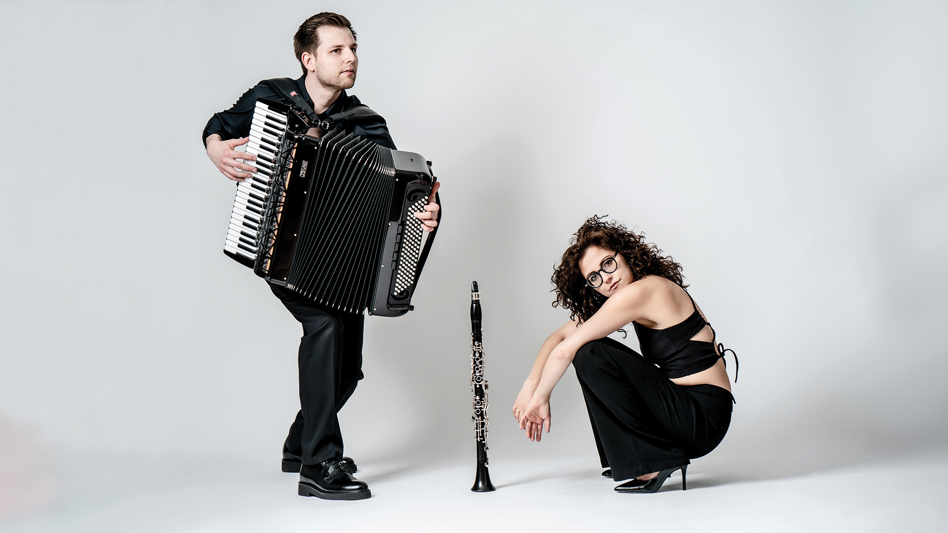Kulturtipps: Mann mit einer Zieharmonika und eine hockende Frau – dazwischen steht eine Oboe am Boden. Beide sind schwarz gekleidet