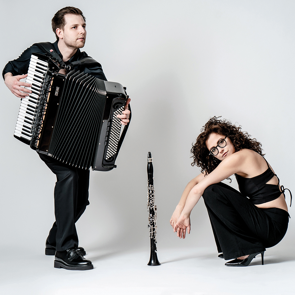 Kulturtipps: Mann mit einer Zieharmonika und eine hockende Frau – dazwischen steht eine Oboe am Boden. Beide sind schwarz gekleidet
