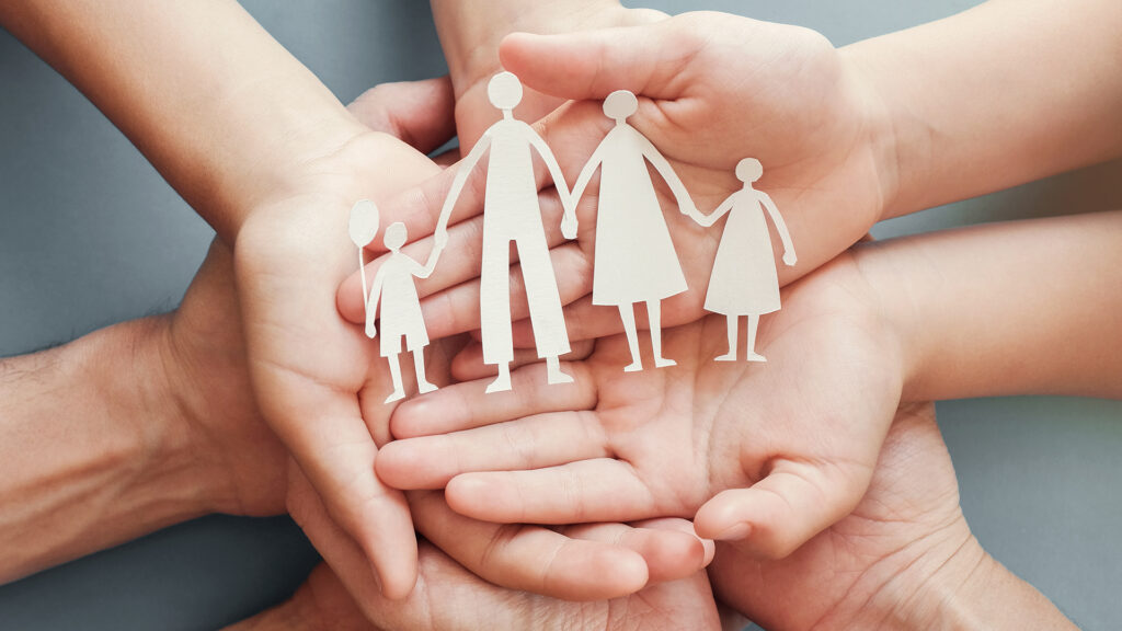 Pflege: Erwachsener und Kinder halten eine aus Papier ausgeschnittene Familiensilhoutte