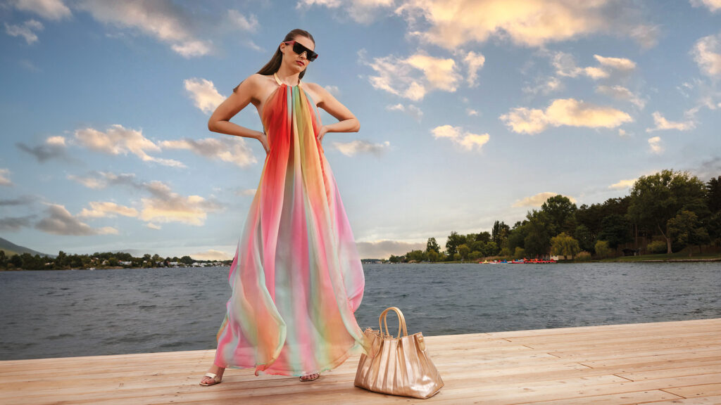 Sommermode: Frau in bunt gestreiftem, langem Hängerchen-Kleid am Steg an einem See