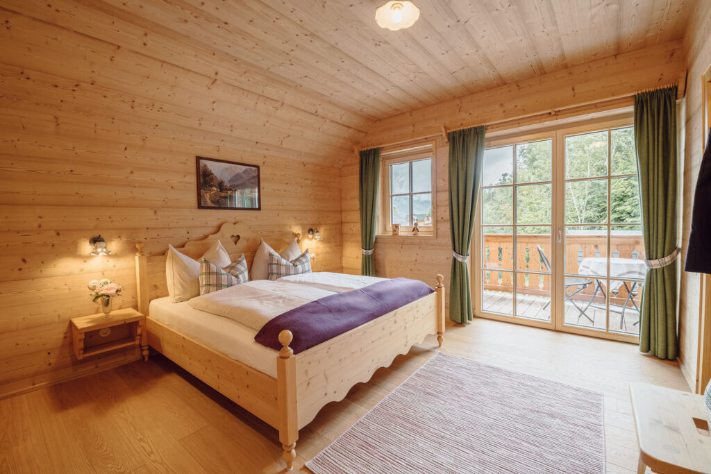 Doppelbet aus Holz in einem mit Holz ausgekleidetem Ferienzimmer