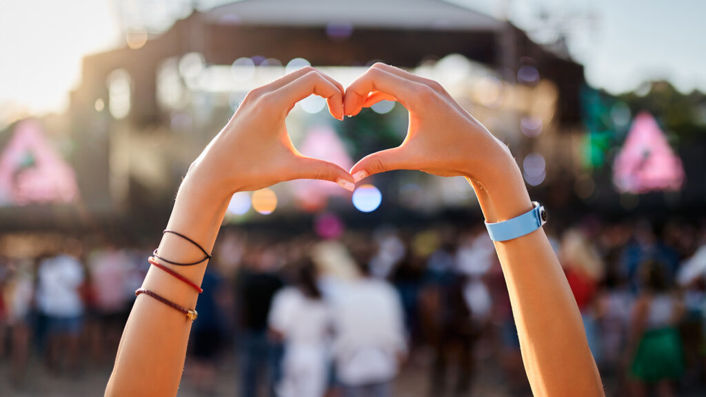 Event-Tipps im Sommer: Open-Air-Konzert – 2 Hände formen ein Herz-Symbol im Vordergrund