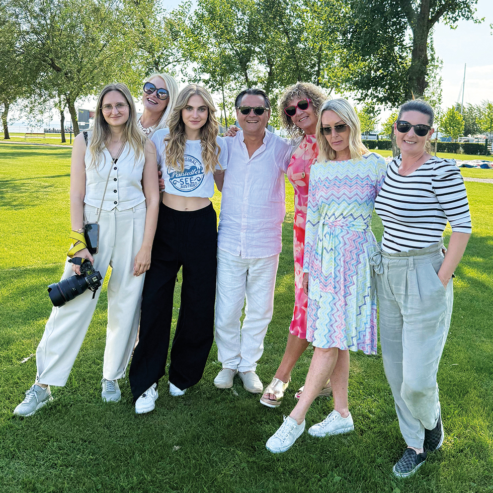 Sommershooting: 6 Frauen und ein Mann in der Mitte – alle umarmt – stehen auf einer Wiese