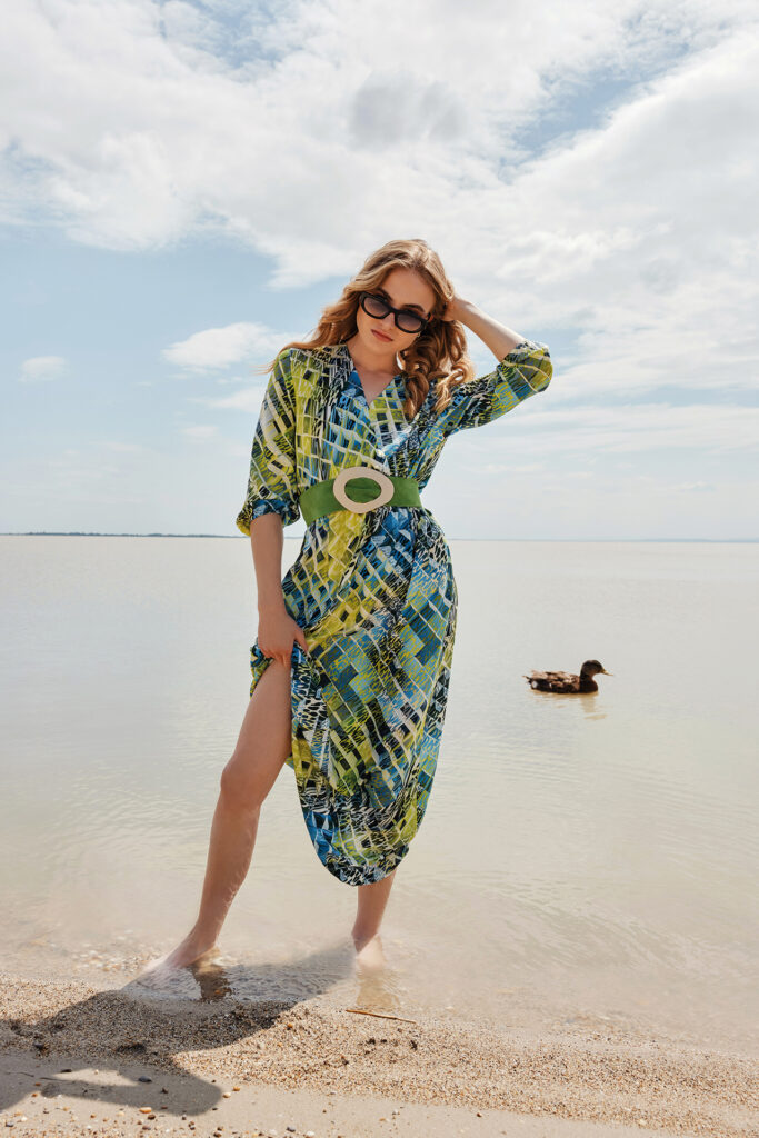 Sommershooting: Junge Dame in einem blau-grün-gelb gemustertem Jersey-Kleid am Ufer eines Sees