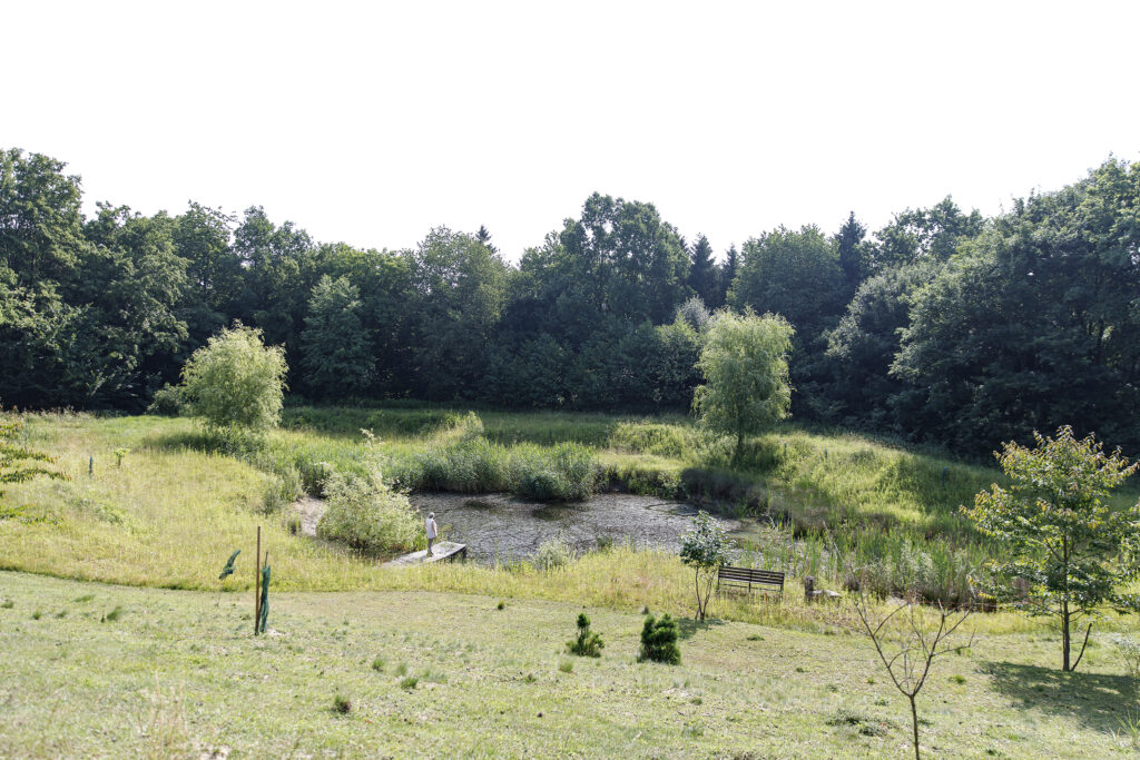 Judith Anger: Frau steht auf einem Steg an einem kleinen Teich