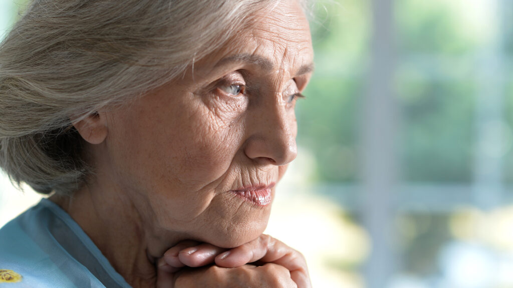 Demenz: Nahaufnahme einer grauhaarigen Seniorin die nachdenklich ihren Kopf aufstützt