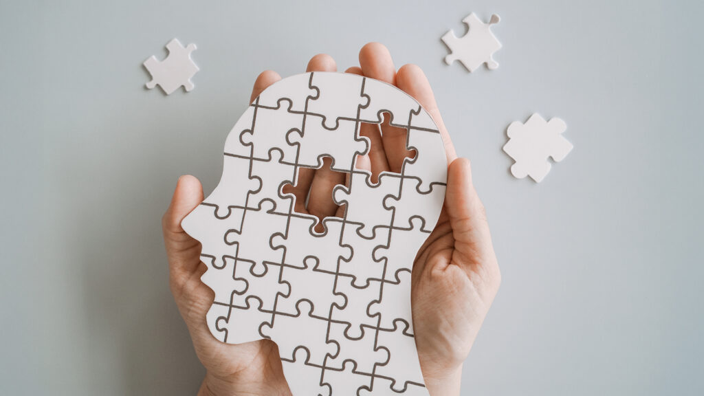 Alzheimer: Hände halten ein Gehirn mit Puzzle-Papierschnitt, Autismus-, Demenz-, Epilepsie- und Alzheimer-Bewusstsein, Anfallsleiden, Welt-Mentalgesundheitstag-Konzept