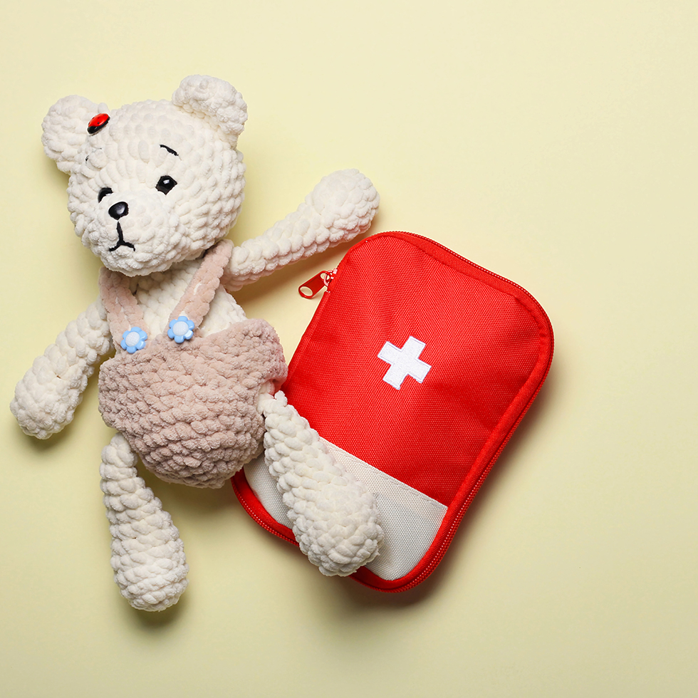 Teddybär und Erste-Hilfe-Set auf hellem Hintergrund – perfekt für Aktivitäten zur Gesundheit und zum Wohlbefinden von Kindern.