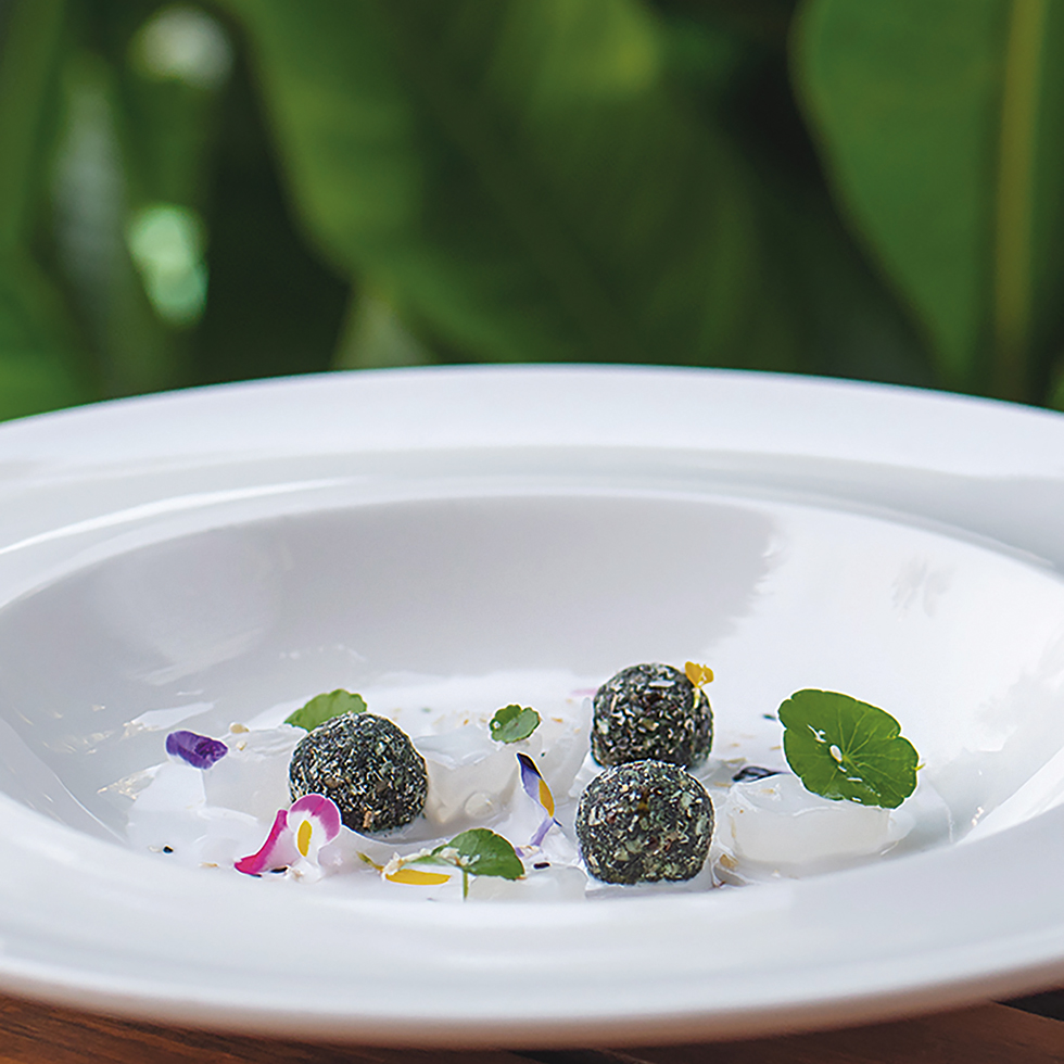 Detox: Weiße Sauce mit drei grünen Kräuterbällchen, Blüten und Kräuterdekor.