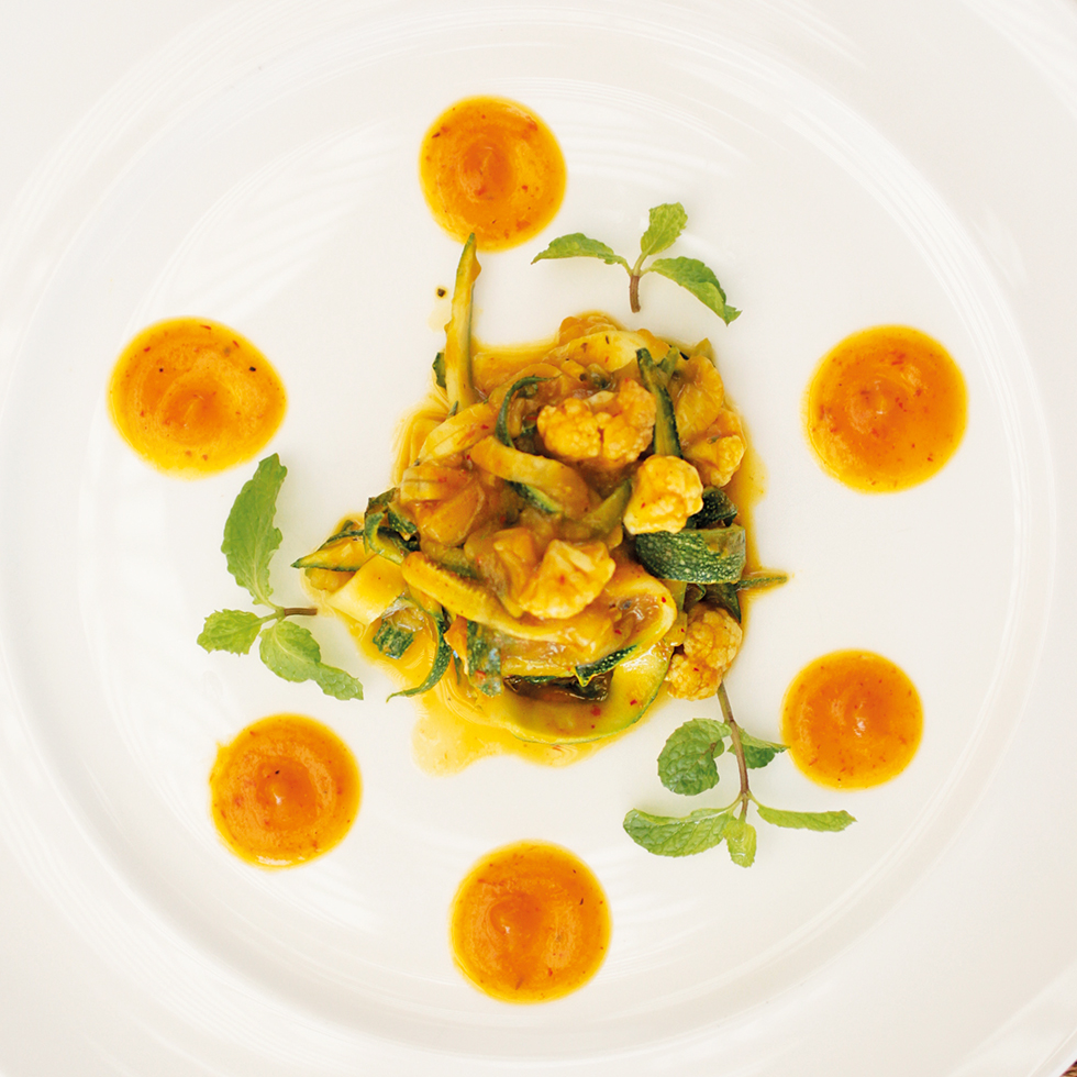 Detox: Zucchini-Nudeln mit Gemüse und Currysauce, kunstvoll angerichtet mit Minze und Saucenpunkten.