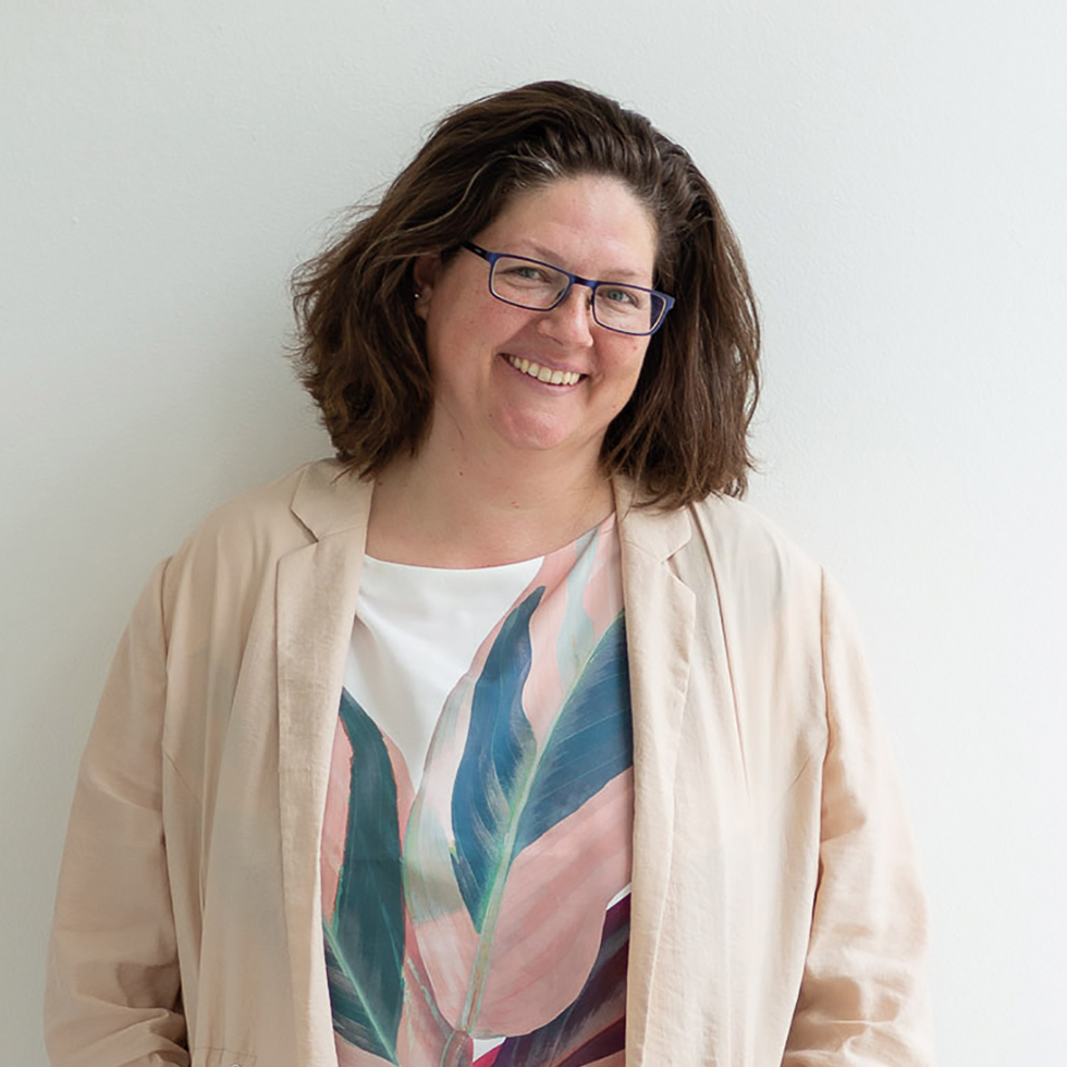Demenz: Portrait einer lachenden Dame mit blauer Brille und hellem Blazer