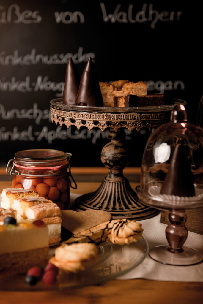 Close-up von einer Etagére mit kleinen süßen Teilchen und einem Teller mit Keksen und Kuchen im Vordergrund