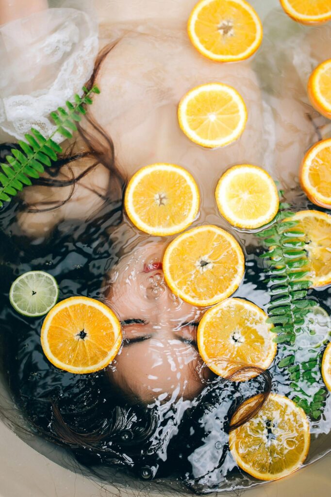 Longevity: Asiatische Frau liegt unter Wasser in Badewanne mit Orangenscheiben im Wasser.