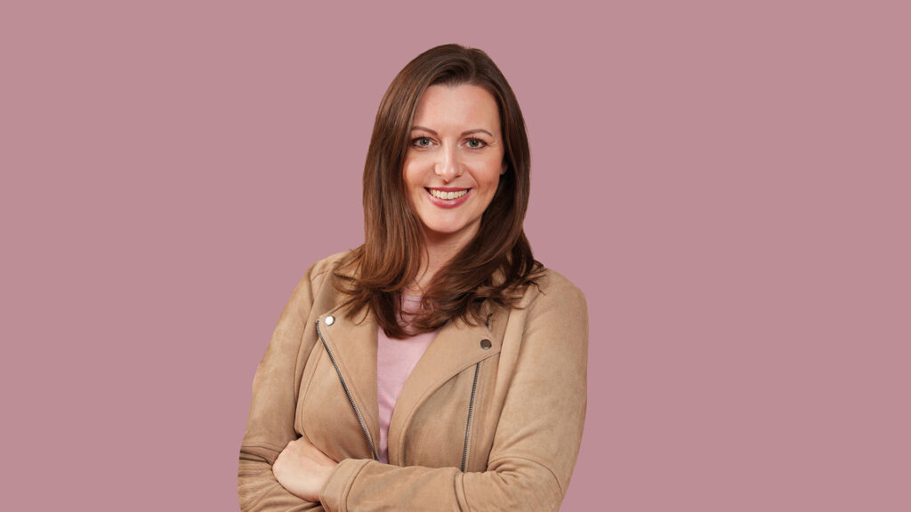 Frau in hellbrauner Lederjacke auf rosa Hintergrund