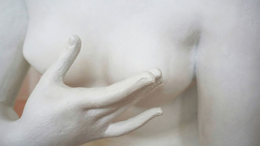 Steinbrüste einer Skulptur und eine Steinhand davor