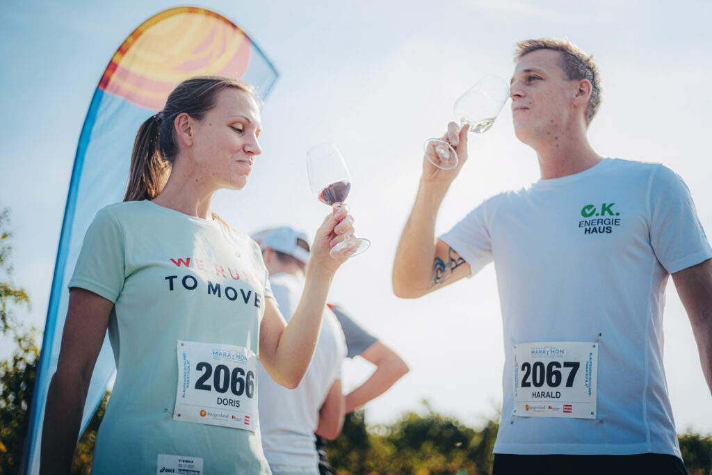Männlicher und weibliche Läuferin trinken ein Glas Wein nach dem Lauf