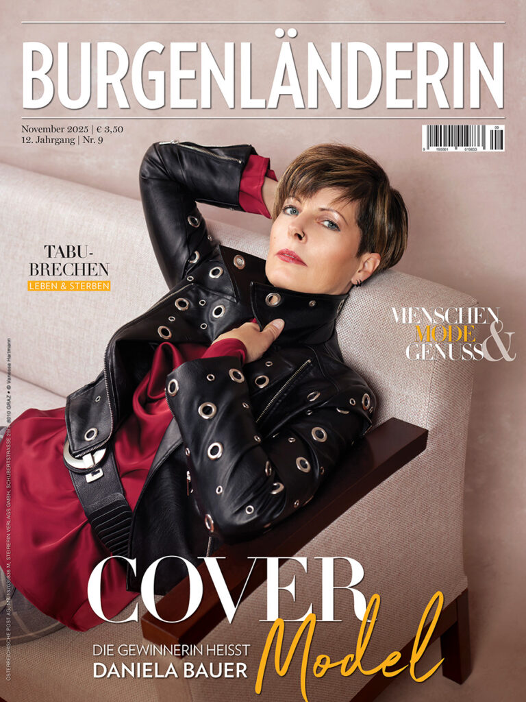Magazincover der BURGENLÄNDERIN – kurzhaarige Frau mit schwarzer Lederjacke und rotem Kleid sitzt gemütlich am Sofa