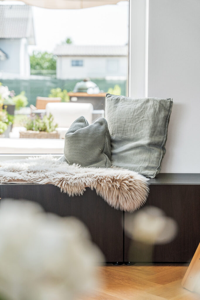 Gemütliche Fensterbank mit Kissen und Fell im modernen Wohnzimmer