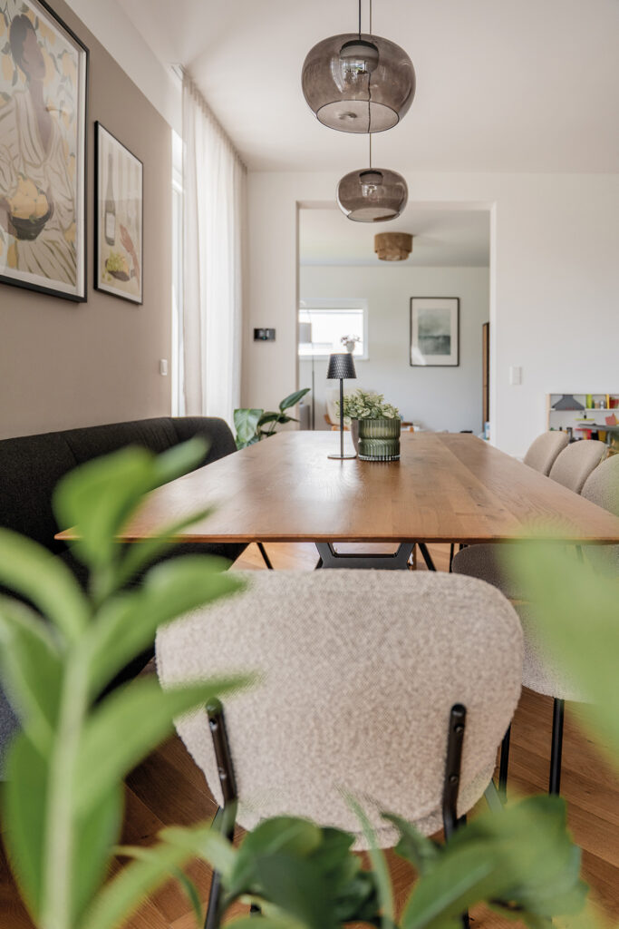 Esszimmer mit großem Holztisch, modernen Stühlen und Wandbildern