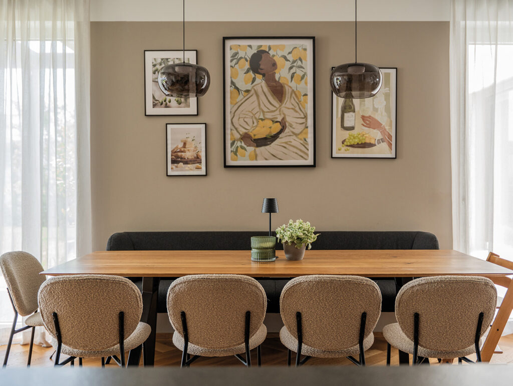 Modernes Esszimmer mit großem Holztisch, Polsterstühlen und dekorativen Wandbildern