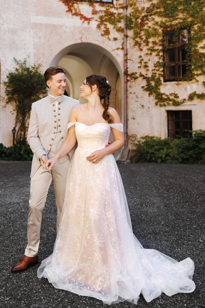 Glückliches Brautpaar in traditionellem Hochzeitsoutfit im Schlossinnenhof