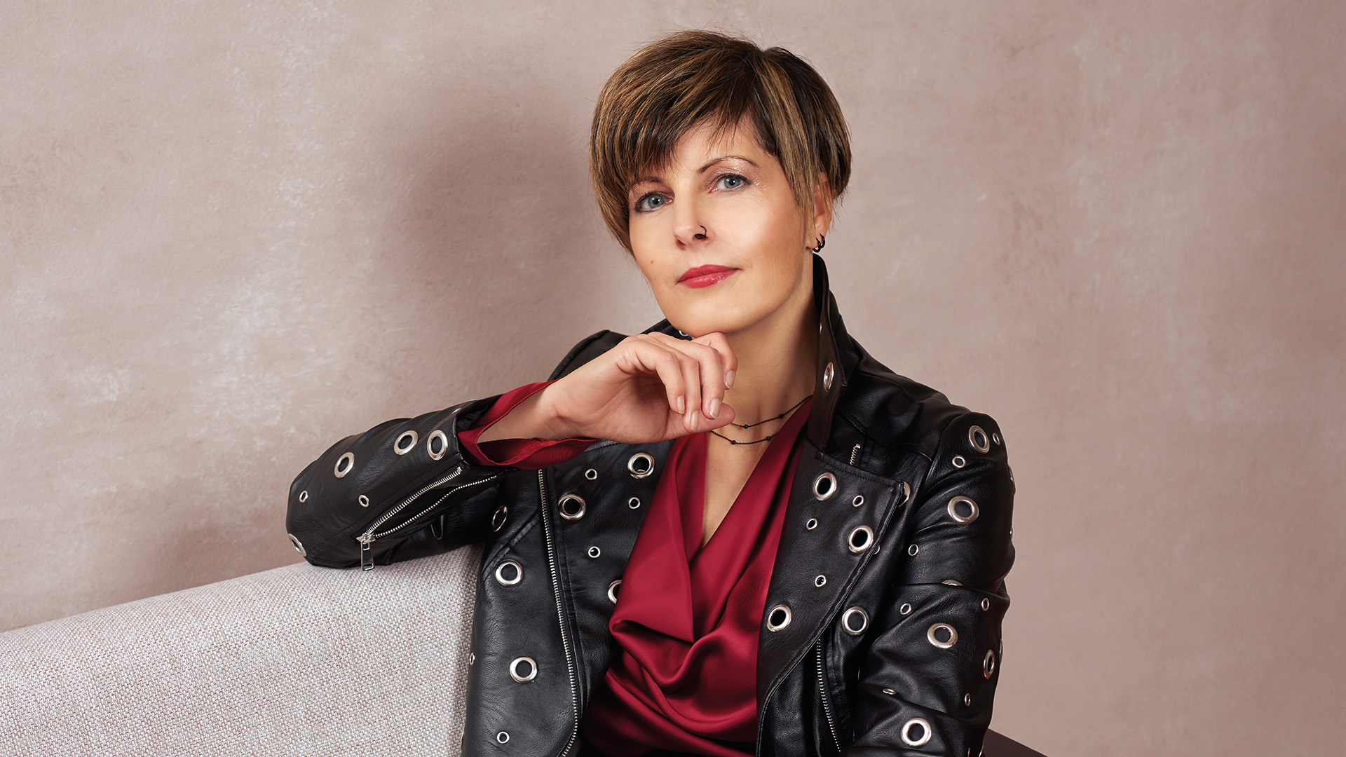 Daniela Bauer: Gewinnerin des Covershootings 2025 – Kurzhaarige Frau mit Nasenring und Hand am Kinn lehnt am Sofa