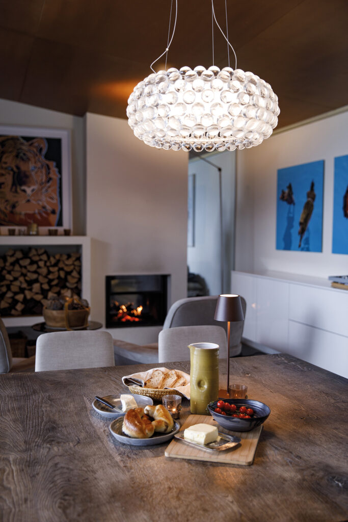 Villa: Detailaufnahme eines Esstisches mit Frühstück, im Hintergrund Kamin und Kunst