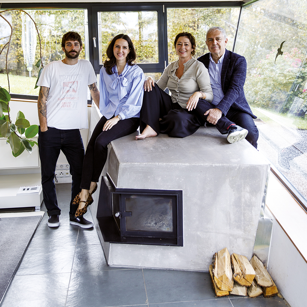 Vier Personen sitzen und stehen um einen modernen Kamin im Wohnzimmer