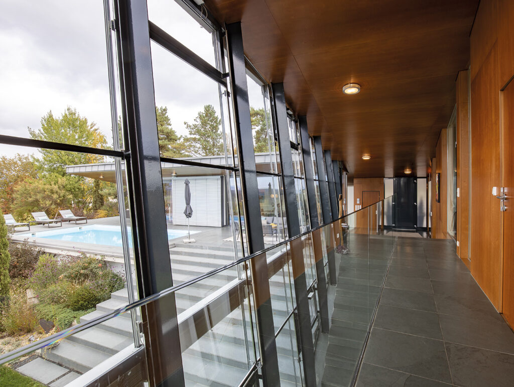 Villa: Gang mit Glaswänden und Blick auf Terrasse und Poolbereich