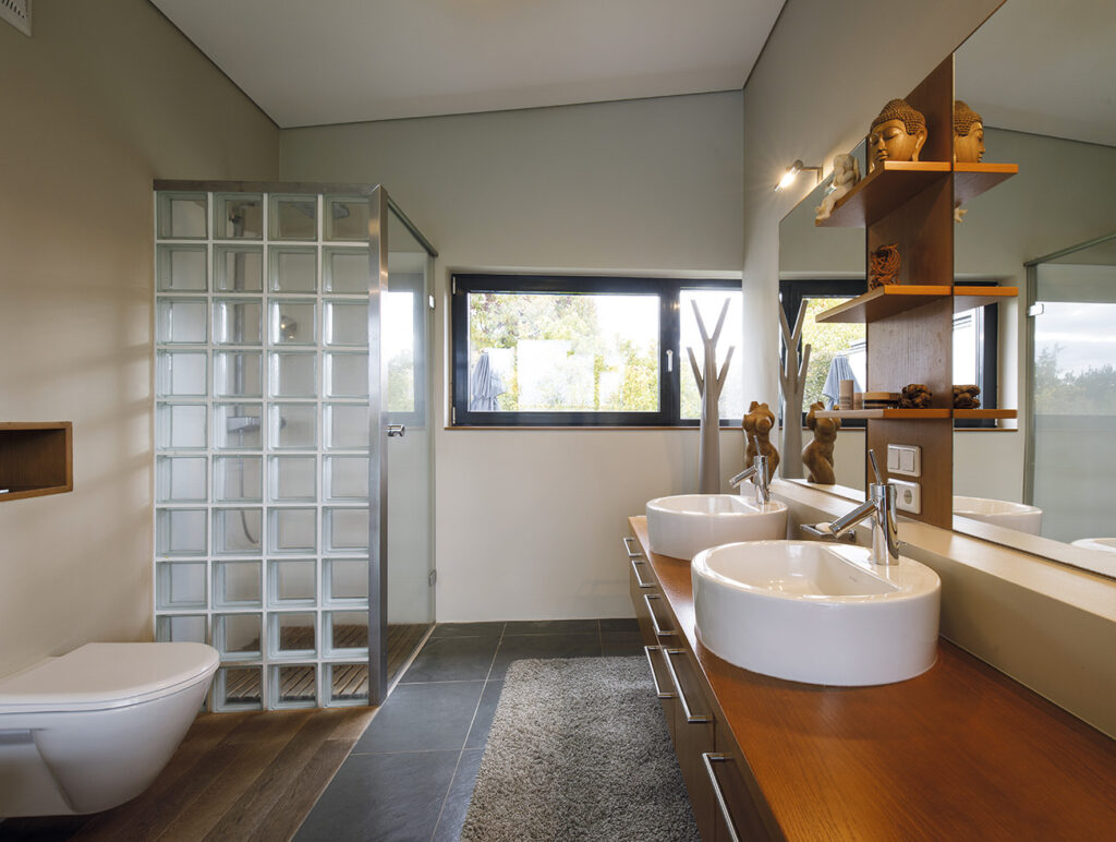 Badezimmer mit Glasdusche, Doppelwaschbecken und Holzdetails
