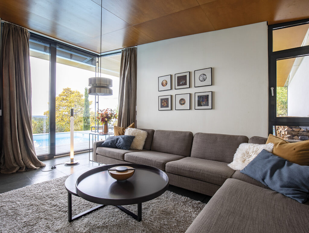 Helles Wohnzimmer mit großer Couch und Blick auf den Pool