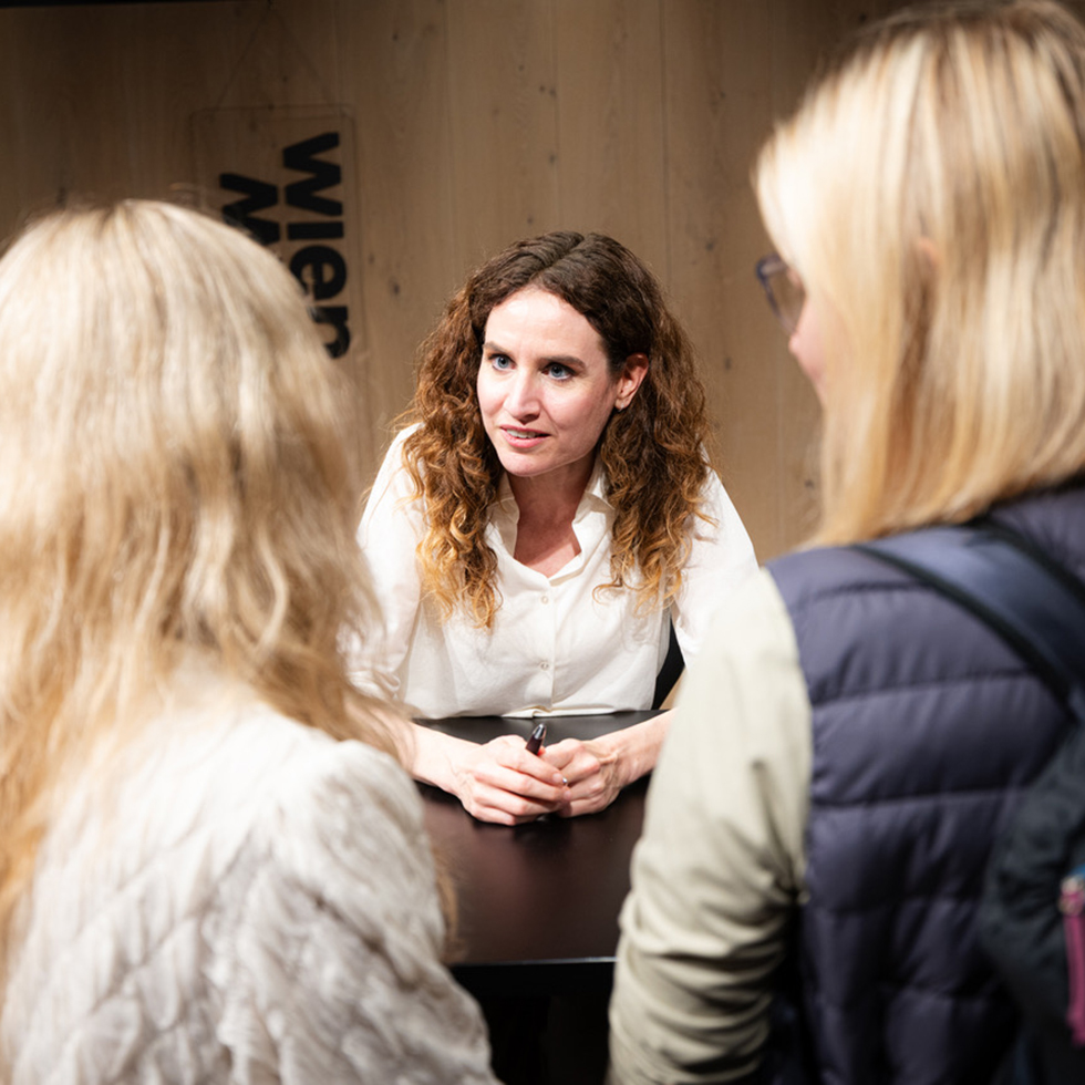 Judith Kohlenberger: Frau im Gespräch mit zwei Besucherinnen bei einer Signierstunde.