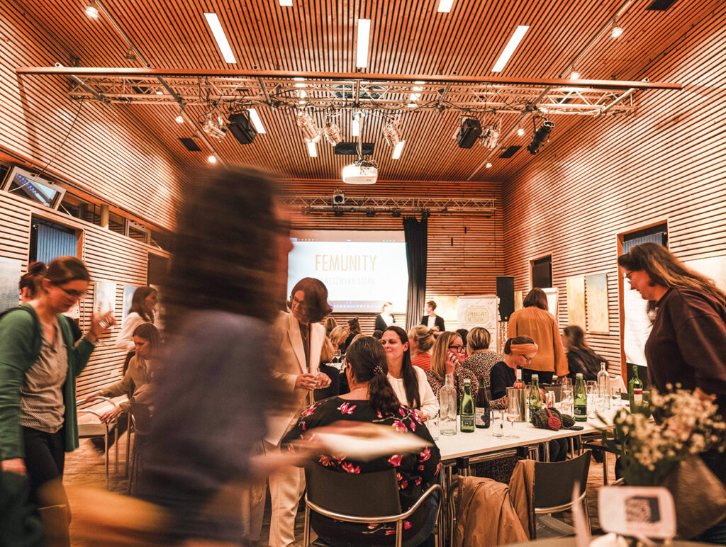 Belebte FEMUNITY-Veranstaltung in einem Saal mit vielen Teilnehmerinnen.“