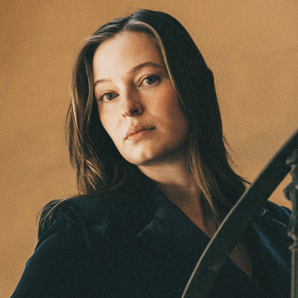 BURGENLÄNDERIN AWARDS VOTING: Portrait einer Frau mit großen grünen Augen, langem, glatten Haar vor einer beigen Wand