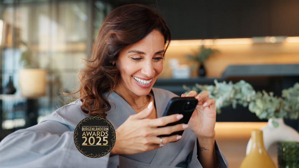 Awards 2026: Frau schaut lächelnd auf ein Mobiltelefon + BURGENLÄNDERIN AWARDS LOGO