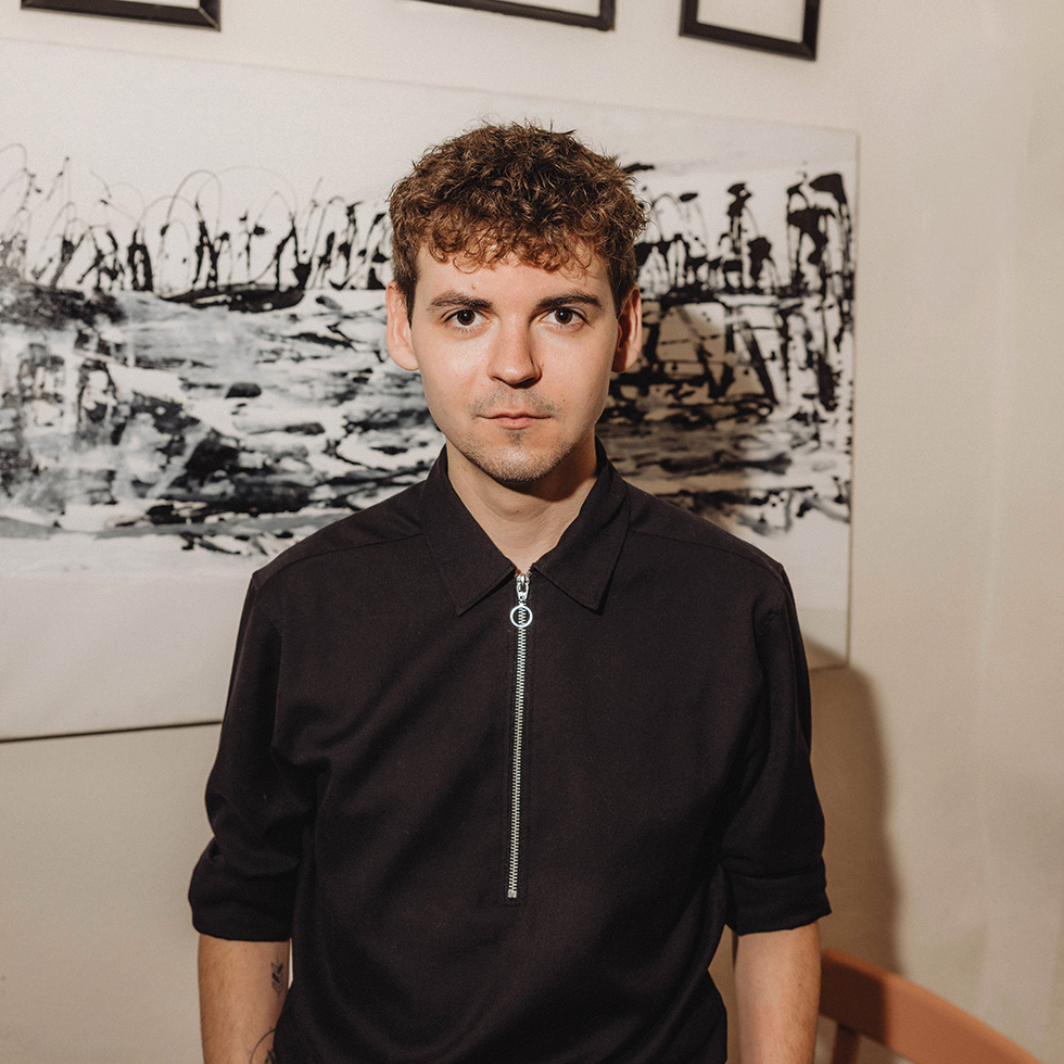 Porträt von Michael Steiger in Innenraum mit Kunst im Hintergrund.