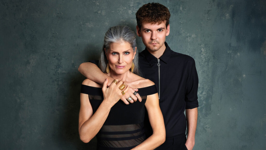 Schmuck-Shooting: Frau und Mann posieren gemeinsam vor dunklem Studiohintergrund und präsentieren Schmuckstücke.