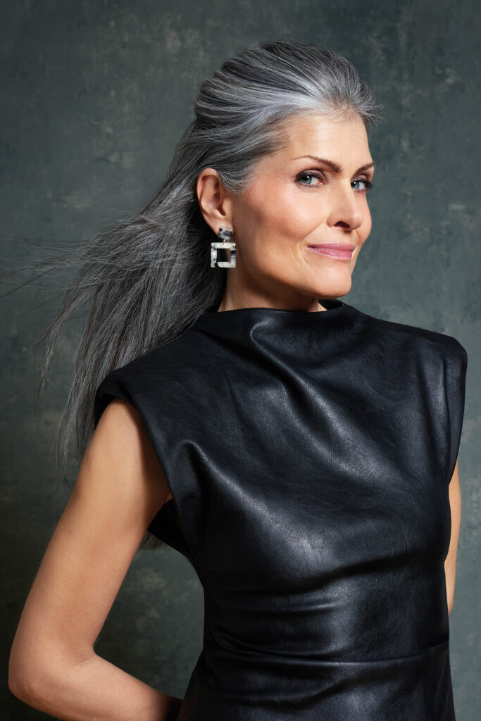 Schmuck-Shooting: Profilporträt einer Frau mit grauem Haar und auffälligen 4-eckigen Ohrringen.