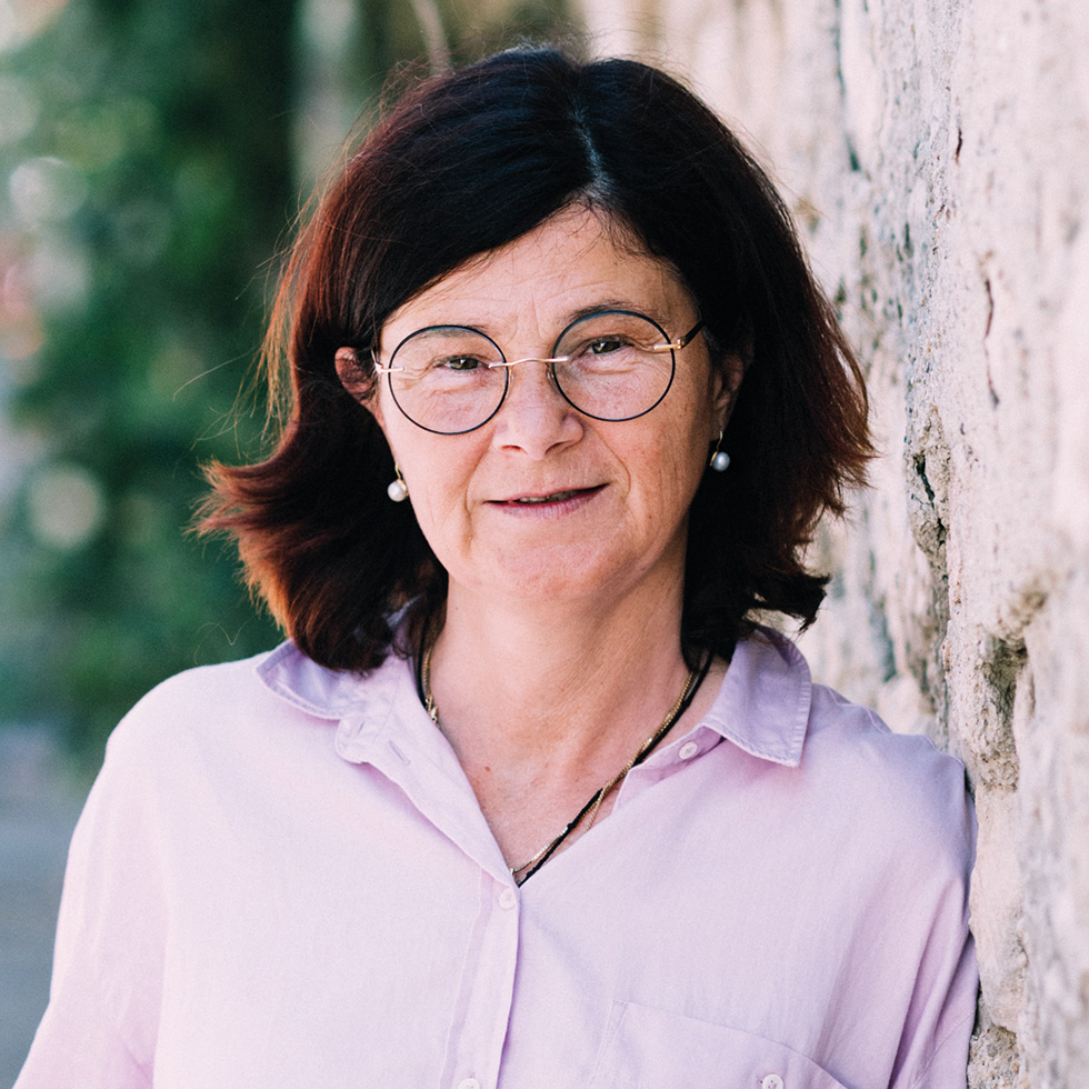 BURGENLÄNDERIN AWARDS VOTING: Portrait einer älteren Frau mit Perlenohrringen, Brille und lila Bluse