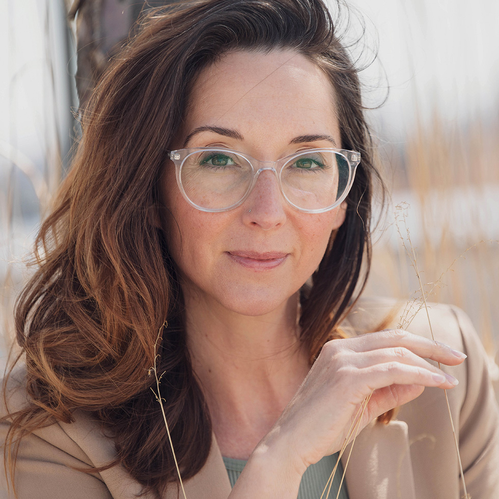 Portrait einer Frau mit transparenter Brille in beigem Blazer