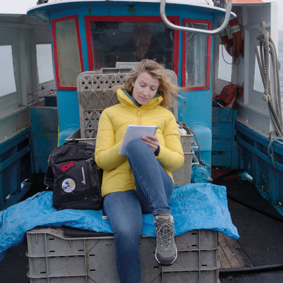 Kulturtipps: Frau schreibt Notizen auf kleinem Boot bei rauer See