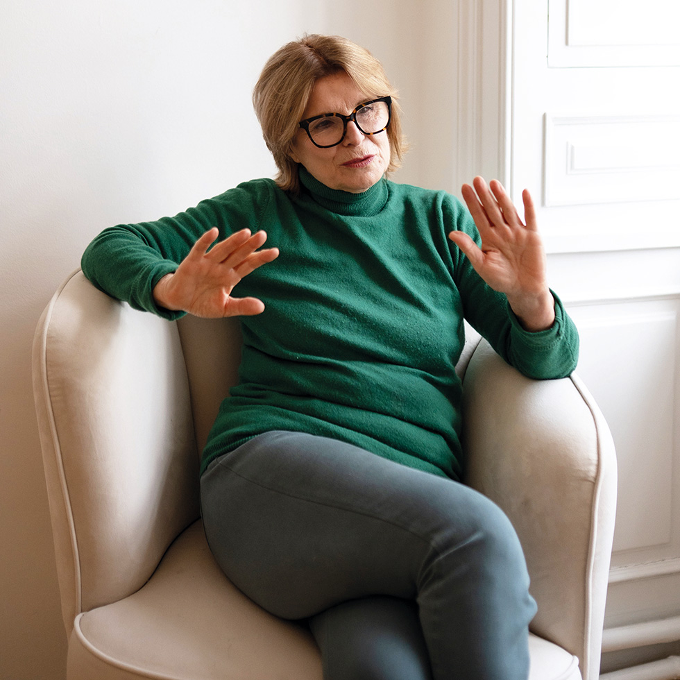 Edit Schlaffer: Frau mit Brille und grünem Rollkragenpullover gestikuliert beim Sprechen