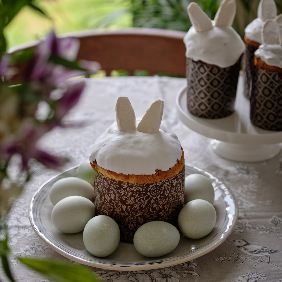 Ostergebäck mit Hasenohren und dekorierten Eiern auf gedecktem Tisch