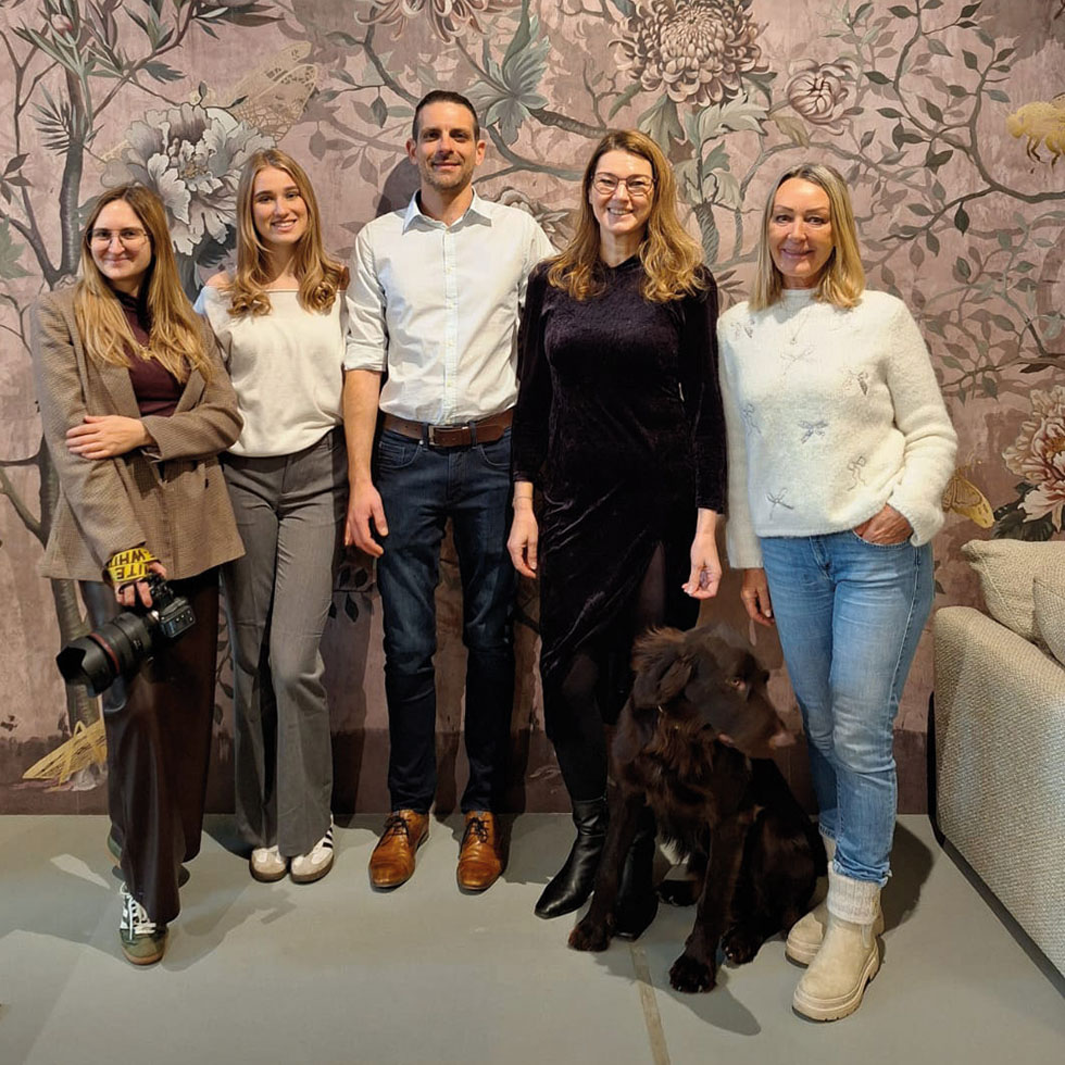 Brillenshooting: Teamfoto mit Fotograf:in und Model vor floralem Hintergrund