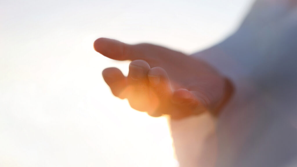 Letzte Hilfe: Hand im Gegenlicht greift nach oben ins warme Licht